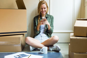 Studentin sitzt in Wohnung mit Umzugskartons