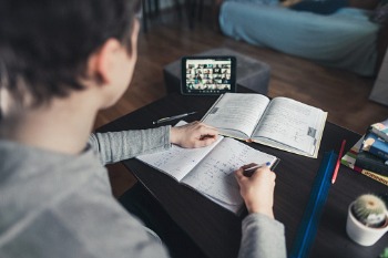 Student sitzt mit Lernmaterial vor Online-Seminar