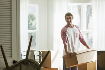 Student mit Umzugskarton in Wohnung