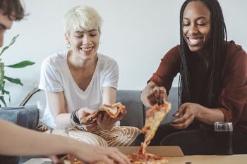 Mitbewohner essen zusammen Pizza.